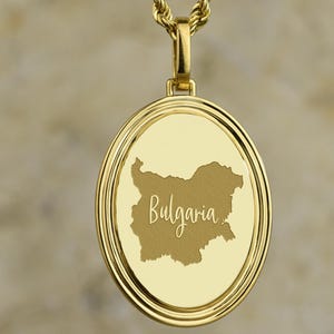 Peut inclure: Collier avec pendentif doré. Le pendentif circulaire représente le contour de la Bulgarie et le nom du pays en écriture cursive. Le pendentif est suspendu à une chaîne en or. Le fond est une surface texturée neutre.