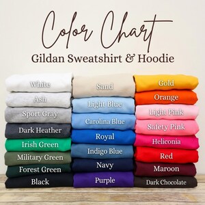 Pu&ograve; includere: Tabella colori per felpe e felpe con cappuccio Gildan. L'immagine mostra pile di felpe piegate in vari colori, tra cui bianco, grigio, blu, verde e rosa. Il testo sull'immagine elenca i nomi dei colori.