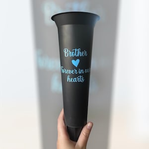 May include: Black plastic flower vase with a blue inscription that reads "Brother forever in our hearts" with a blue heart symbol.