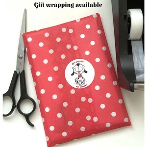 May include: Red gift wrapping paper with white polka dots. A sticker with a cartoon dog and the text "get ready to smile" is on the paper.