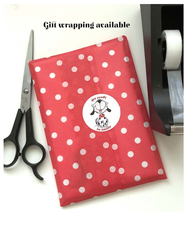 May include: Red gift wrapping paper with white polka dots. A sticker with a cartoon dog and the text "get ready to smile" is on the paper.