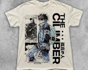 May include: Off-white t-shirt featuring a manga-style illustration of a climber with the text "THE CLIMBER" and Japanese characters. The shirt also includes the text "YES. I'LL PROBABLY ALWAYS BE ALONE."