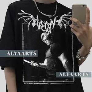 Könnte beinhalten: Schwarzes T-Shirt mit einer Schwarz-Weiß-Grafik einer Person, die ein Messer hält, dem Text "YOUR RIGHT HAND COMES OFF?" und dem Markennamen "ALYAARTS". Das T-Shirt hat auch ein dekoratives Design oben.