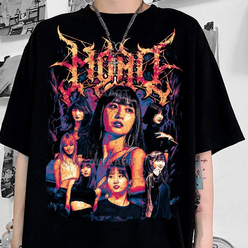 May include: Black graphic t-shirt featuring a colorful design with multiple portraits of women and the word "Zombie" in a stylized font. The design incorporates shades of red, orange, blue, and purple.
