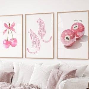 May include: Three framed art prints with light wood frames. The prints feature a watercolour cherry design, pink cheetahs, and two pink glitter pool balls with the number 8 and the text "lucky me".