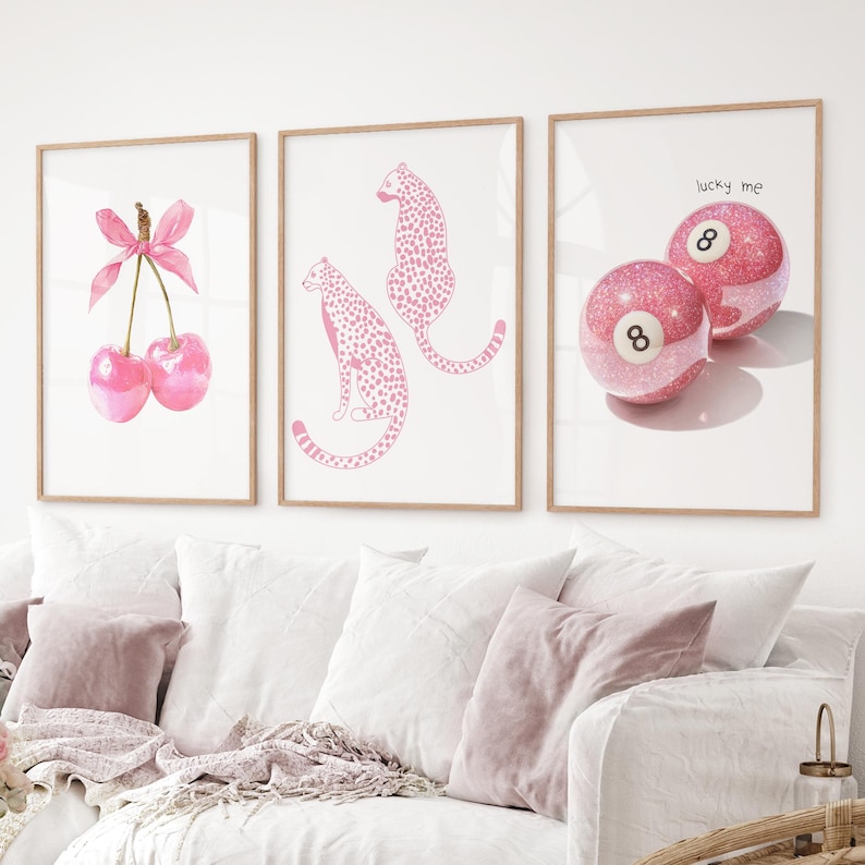 May include: Three framed art prints with light wood frames. The prints feature a watercolour cherry design, pink cheetahs, and two pink glitter pool balls with the number 8 and the text "lucky me".