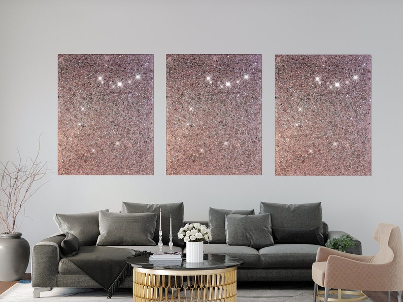 Puede incluir: Tres lienzos cuadrados con un fondo de purpurina rosa. Los lienzos est&aacute;n colgados en una pared blanca sobre un sof&aacute; gris.