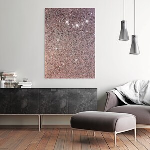 Puede incluir: Un interior de sala de estar moderno con un gabinete negro, un otomano gris y una manta blanca sobre un sill&oacute;n gris. Una impresi&oacute;n de lienzo de brillo rosa y blanco cuelga de la pared sobre el gabinete. Dos luces colgantes plateadas cuelgan del techo.