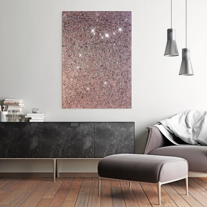 Puede incluir: Un interior de sala de estar moderno con un gabinete negro, un otomano gris y una manta blanca sobre un sill&oacute;n gris. Una impresi&oacute;n de lienzo de brillo rosa y blanco cuelga de la pared sobre el gabinete. Dos luces colgantes plateadas cuelgan del techo.