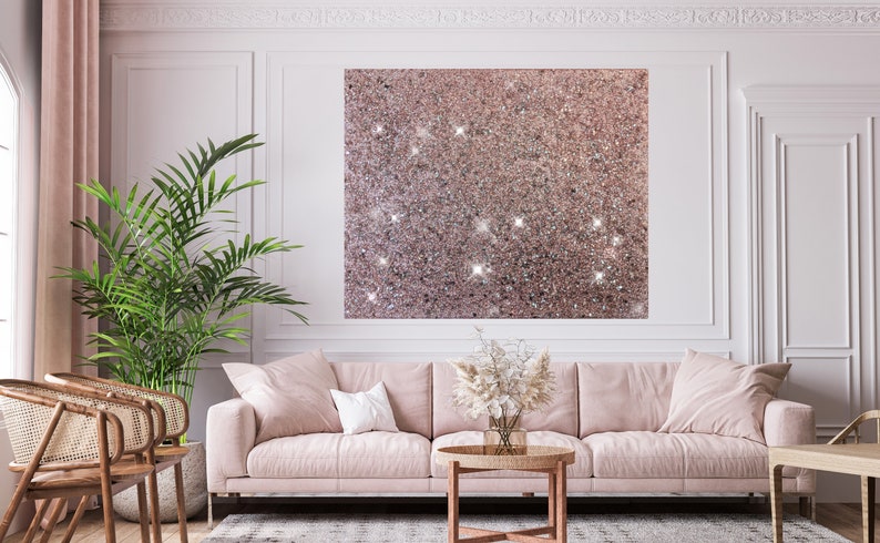 Puede incluir: Un sof&aacute; rosa con un coj&iacute;n blanco en una sala de estar con una gran obra de arte de pared de purpurina rosa, una planta en maceta y una mesa de caf&eacute; con un jarr&oacute;n de flores secas.