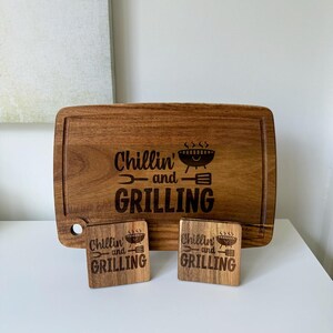 May include: A wooden cutting board with the text "Chillin' and Grilling" engraved on it. Two smaller wooden coasters with the same text are also included.