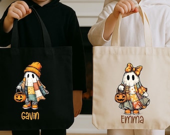 May include: Two rectangular canvas tote bags, one black and one off-white, each featuring a graphic of a ghost wearing a patchwork blanket and holding a jack-o'-lantern. The black bag displays the name Gavin, and the off-white bag displays the name Emma.