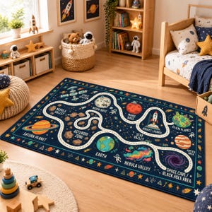 Könnte beinhalten: Ein rechteckiger Teppich mit einem dunkelblauen Weltraum-Design und einem geschwungenen weißen Pfad, der verschiedene Himmelskörper wie Saturn, Erde, Mars und eine Raketenstartrampe verbindet, beschriftet mit Texten wie Asteroid Zone und Space Station.