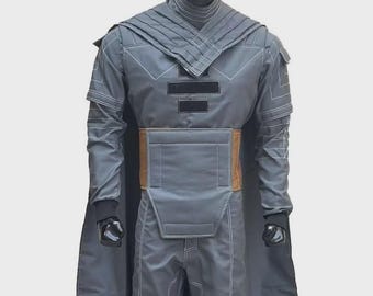 May include: A gray full-body costume featuring a high-collared jacket with structured shoulder panels, a tan waist belt, and matching trousers. The ensemble includes a long cape and white contrast stitching throughout the fabric design.