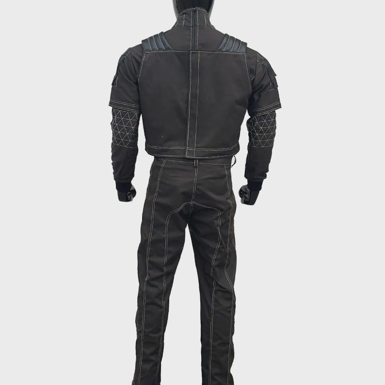 Puede incluir: Un conjunto de chaqueta y pantal&oacute;n de estilo t&aacute;ctico en color negro con costuras blancas en contraste. La chaqueta incluye hombreras, cuello alto y patrones geom&eacute;tricos de l&iacute;neas blancas en las mangas. El pantal&oacute;n tiene un corte recto.