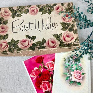 May include: A vintage gift box with the words "Best Wishes" in elegant script, surrounded by pink roses and green leaves. Two greeting cards with floral designs are also visible, one with red roses and the other with pink roses.