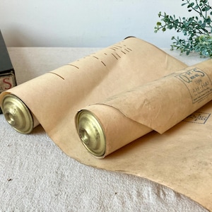 May include: Vintage music roll with the text "Q.R.S. Word Roll AH-HA!" and a black box with text. The roll is tan with brass end caps. The box has the text "Q.R.S. Word Roll" and other text.