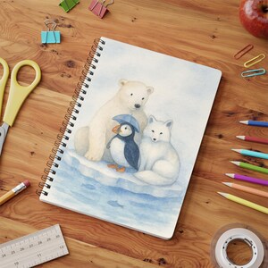 Op de afbeelding: Spiraalgebonden notitieboek met een aquarel illustratie van een ijsbeer, poolvos en papegaaiduiker met een blauwe hoed. Het notitieboek heeft een witte kaft met een kleurrijk ontwerp.