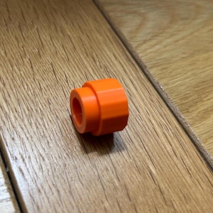 May include: Orange plastic connector with a round hole in the centre.