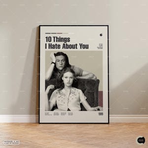 Könnte beinhalten: Ein gerahmtes Filmplakat für "10 Things I Hate About You" mit zwei Schauspielern. Das Plakat hat einen beigen Hintergrund mit dem Titel in großen, fetten Buchstaben. Das Jahr 1999 steht unten. Das Plakat ist in einem schwarzen Rahmen.