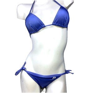 May include: A blue bikini set on a mannequin. The top is a triangle style with halter straps. The bottoms are a low-rise style with tie sides. The bikini is a solid blue color.