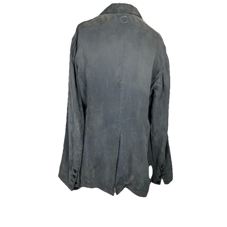 May include: A charcoal gray blazer featuring a collared neckline, long sleeves with four black buttons at each cuff, and a single back vent. The garment has a subtle, weathered texture throughout and a small circular logo detail at the nape.