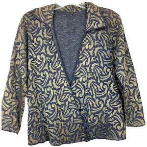 May include: A navy blue jacket with a gold, swirling pattern. The jacket has long sleeves, a collar, and two buttons. The fabric has a textured appearance.