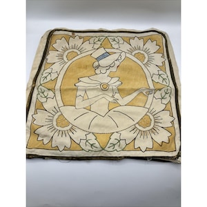 May include: Vintage square pillow with a cream-colored background. The pillow features a central illustration of a woman in a hat, surrounded by a yellow circle and white daisies. The design is outlined in black and green.