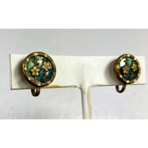 May include: A pair of gold tone clip-on earrings with a green and white enamel design featuring three gold flowers.