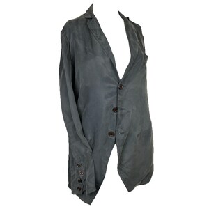 May include: A dark gray blazer featuring a notched lapel, a three-button front closure, and long sleeves with four small buttons on each cuff. The garment has a smooth, slightly textured appearance with a structured collar and a straight hemline.