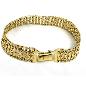 May include: A gold-toned bracelet with a repeating openwork design. The bracelet features a secure clasp closure. The intricate pattern and polished finish give the bracelet a classic and elegant look. This piece of jewelry is suitable for various occasions.