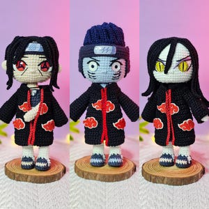 May include: Three handmade crochet dolls, each depicting a character from an anime series. The dolls feature black coats with red cloud accents, and are displayed on wooden slices. Each doll has unique facial features and hairstyles.