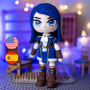 Peut inclure: Poupée au crochet faite à la main avec des cheveux bleus et de grands yeux bleus. La poupée porte une tenue bleue et blanche avec des bottes marron. La poupée a un design détaillé, probablement un personnage de jeu vidéo ou d'anime.