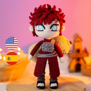 May include: Crocheted doll of a character with red hair, blue eyes, and a red and gray outfit. The doll has a detailed design, including a gray vest and black and white shoes. The doll is handmade and stands on a wooden surface.