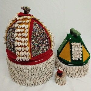 May include: Three decorative hats with intricate designs. The largest hat features a red band, yellow and red panels, and is adorned with white shells and colorful beads. The other two hats are smaller, with green and yellow panels, and white shells.