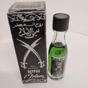 May include: A small, black and silver box with a green glass bottle inside. The bottle has a black cap and is labeled "Seyfou L'Islam" with Arabic text. The box has a silver sword design and the text "5ml Extrait Seyfou L'Islam".