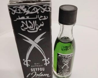 May include: A small, black and silver box with a green glass bottle inside. The bottle has a black cap and is labeled "Seyfou L'Islam" with Arabic text. The box has a silver sword design and the text "5ml Extrait Seyfou L'Islam".