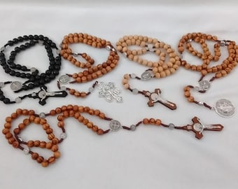 May include: Assortment of rosaries featuring wooden beads in various shades of brown and black. Each rosary includes a crucifix and a centerpiece, some with silver-toned accents. The beads vary in size and shape.