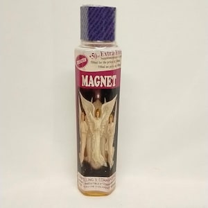 May include: A clear bottle of "MAGNET" cologne with a purple cap and a label featuring an angel illustration. The label also includes the text "Extra Free" and "Eau de Cologne".
