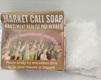 May include: A brown box of "MARKET CALL SOAP" with French text and a crowd image. The box also includes the text "Please kindly try and extend arms to the poor masses or beggars." A wrapped bar of soap is next to the box.