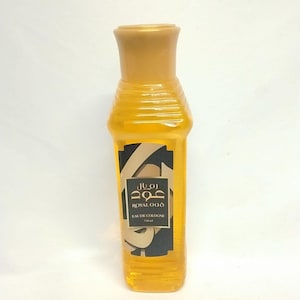 May include: A tall, amber-colored Royal Oud Eau de Cologne bottle with a gold cap. The label features Arabic script and the words "ROYAL OUD" and "EAU DE COLOGNE". The bottle contains 250 ml of cologne.