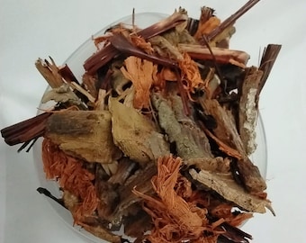 May include: A clear glass bowl filled with a mix of dried herbs and bark. The contents are a mix of brown, tan, and orange hues, with various textures from shredded fibers to woody pieces. The arrangement suggests a natural, organic product.