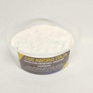 May include: A clear plastic container filled with a white, creamy substance. The container has a label with text in a foreign language, including the words "OSE AWORO ITAJA" and "KARAKATA". The label has yellow and brown accents.