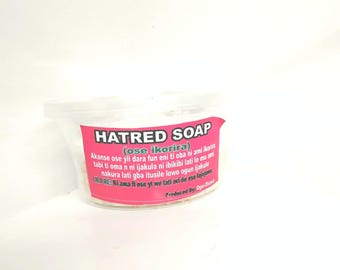 May include: A white plastic container of Hatred Soap. The label is pink and features the product name and additional text in a foreign language. The soap appears to be white and granular.