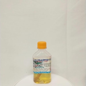 May include: A clear bottle with a yellow cap filled with a golden liquid. The label reads "SELLING & GROUND PUL" and includes directions for use. The bottle is labeled "FROM ZION SPIRITUAL TEMPLE".