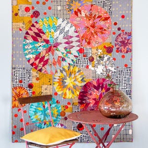 May include: A rectangular quilt featuring a patchwork design of large circular motifs in shades of pink, yellow, teal, and red, layered over a grey background with black grid patterns, musical notes, and scattered red dots throughout the fabric.