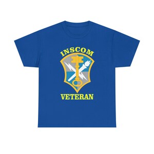 May include: A royal blue t-shirt featuring the text "INSCOM VETERAN" in yellow. The shirt displays a gold key and torch emblem with a lightning bolt and a shield design. This tee is perfect for veterans.