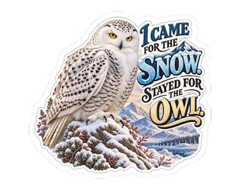 Pode incluir: Um autocolante recortado com uma coruja-das-neves pousada numa rocha coberta de neve com uma paisagem montanhosa ao fundo. O texto diz: I CAME FOR THE SNOW. STAYED FOR THE OWL. A coruja tem penas brancas com manchas pretas e olhos amarelos.