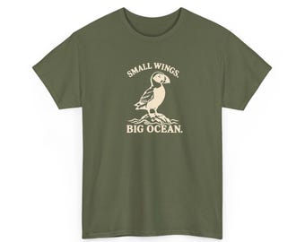 Camiseta com estampa de papagaio-do-mar-atlântico, asas pequenas, oceano grande, ilustração de ave marinha em tons de marfim.