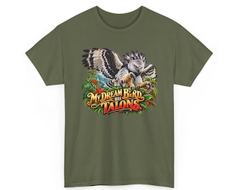 Pode incluir: Uma t-shirt verde-oliva com um gráfico de uma harpia com as asas abertas pousada num ninho de folhas verdes e flores vermelhas. Abaixo da ave, o texto "MY DREAM BIRD HAS TALONS" está escrito numa fonte estilizada em laranja e vermelho.